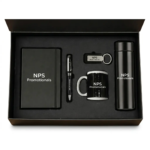 Open black presentation box revealing a matching custom-branded corporate gift set including a notebook, pen, keychain, mug, and thermal flask.