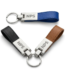 Three custom leather and metal loop keychains in blue, black, and brown, featuring an engravable silver metal plate and a sturdy split ring.